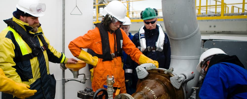 Workers connecting oil terminal supply line to ship for loading oil