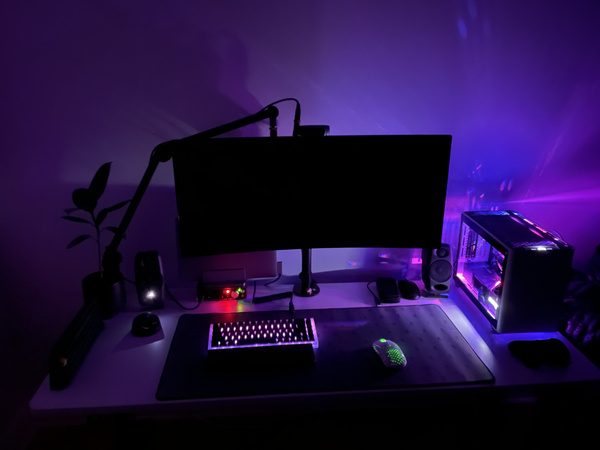 A computer desk with a Cooler Master NR200P with purple lighting