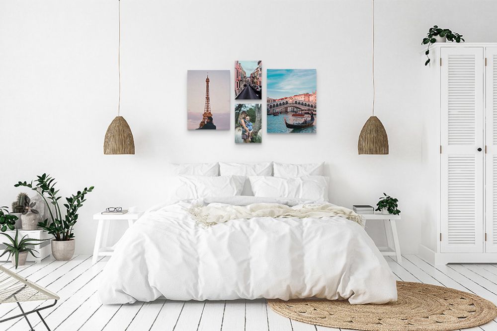 A white bedroom with four travel photos printed on canvas hung above the bed.