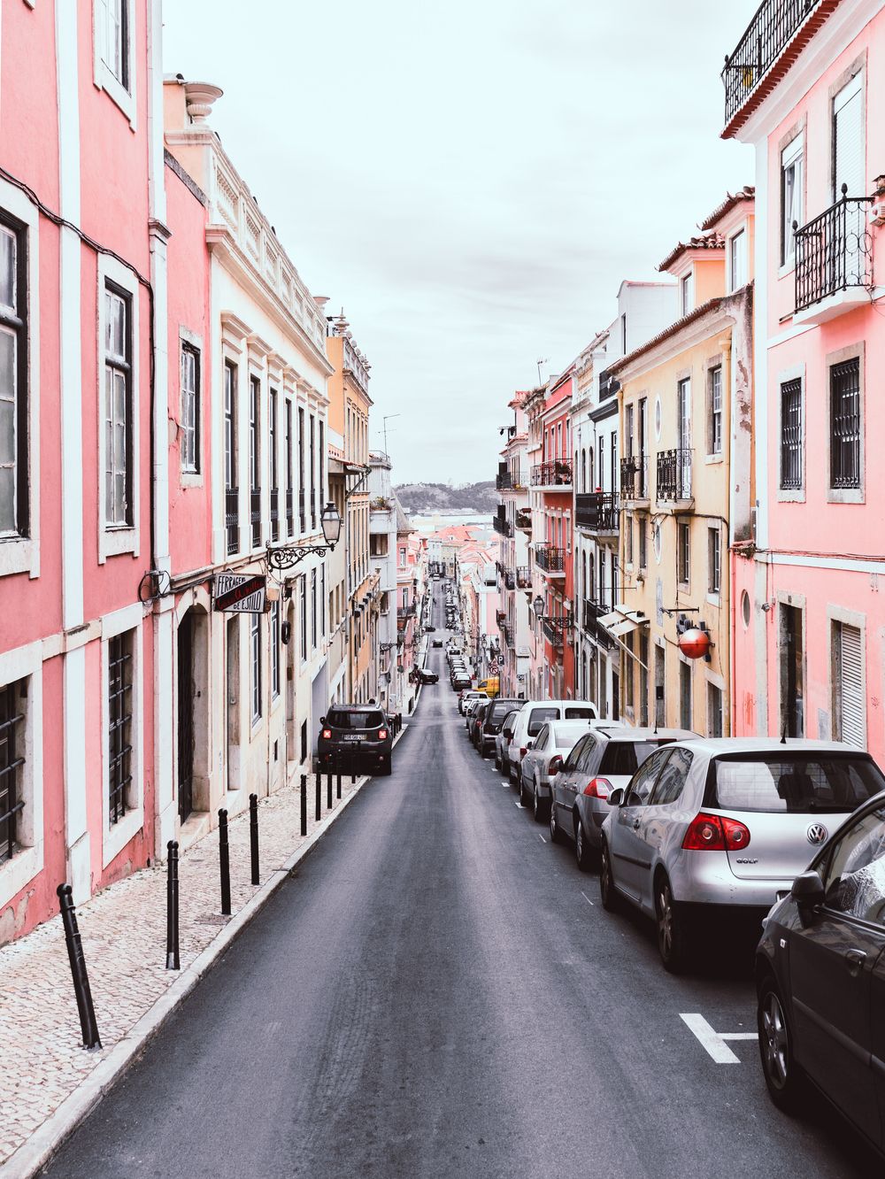European street view of colorful buildings and parked cars.