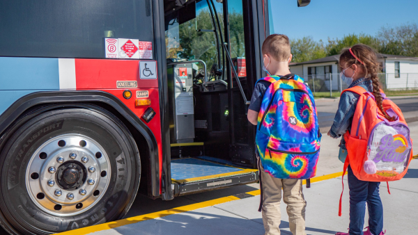 Young children boarding a bus. 