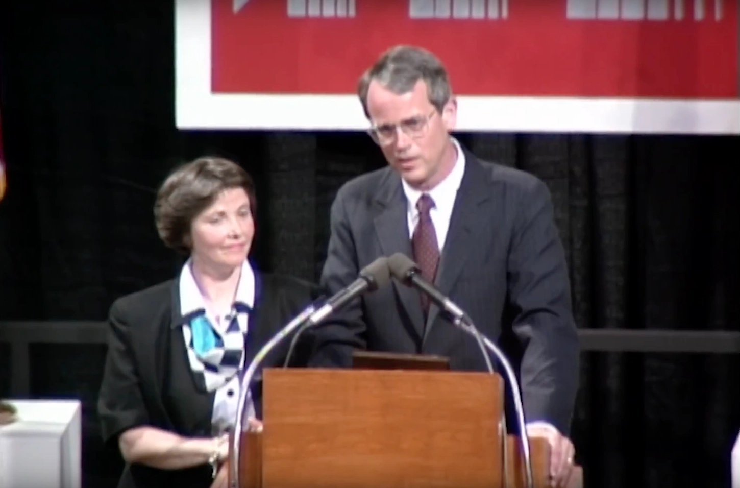 Charles Vest speaking at a podium on stage, in front of a dark background