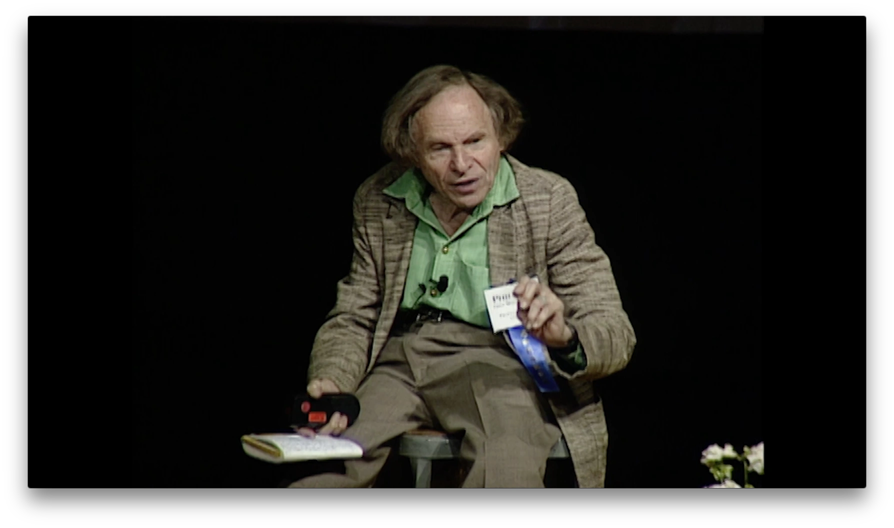 Philip Morrison seated on stage speaking in front of dark background
