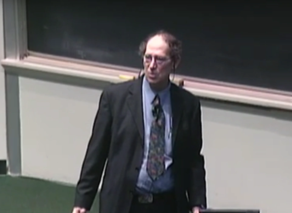 Stephen Schneider lecturing in a classroom, standing in front of a chalkboard .