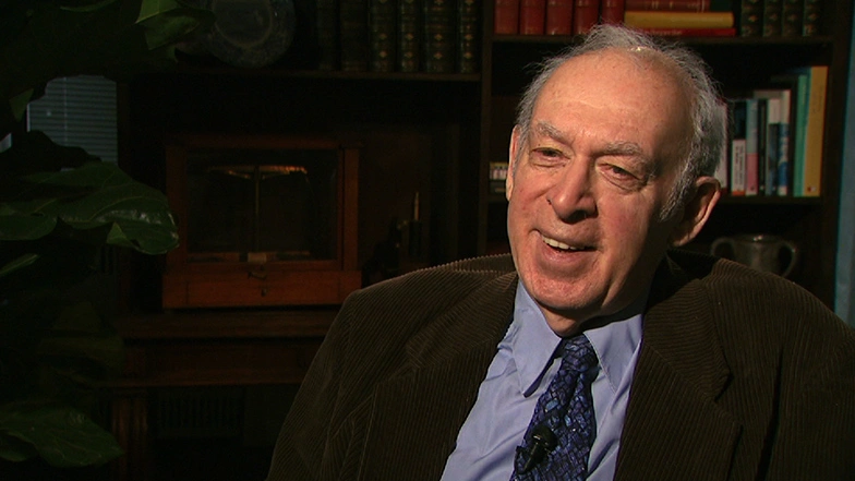 Jerome I. Friedman seated in front of a black background for an on camera interview.
