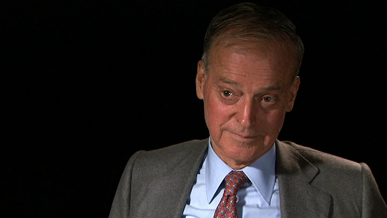 John S. Reed seated in front of a black background for an on camera interview.