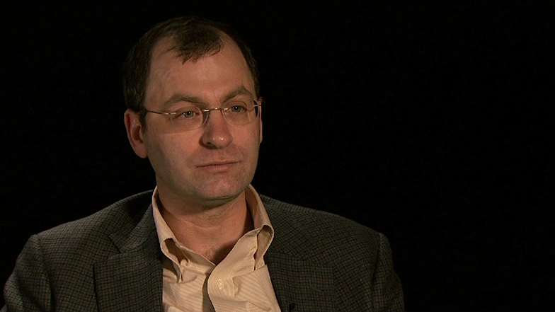 David A. Mindell seated in front of a black background for an on camera interview, smiling