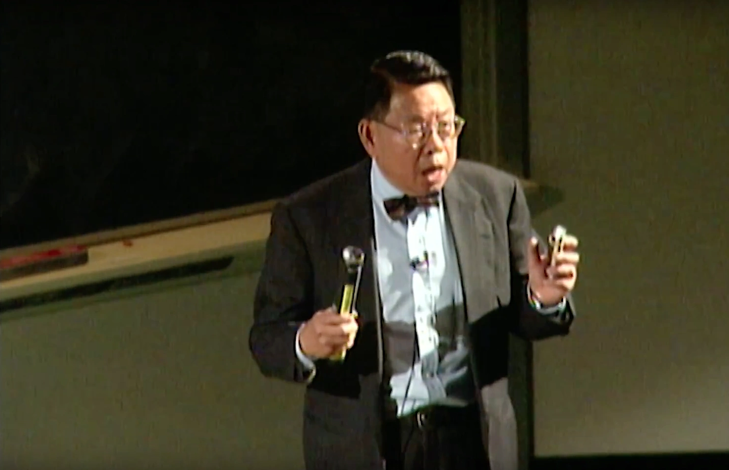 Ming Tsuang, wearing a tuxedo and giving an impassioned lecture in a classroom, a chalkboard in the background