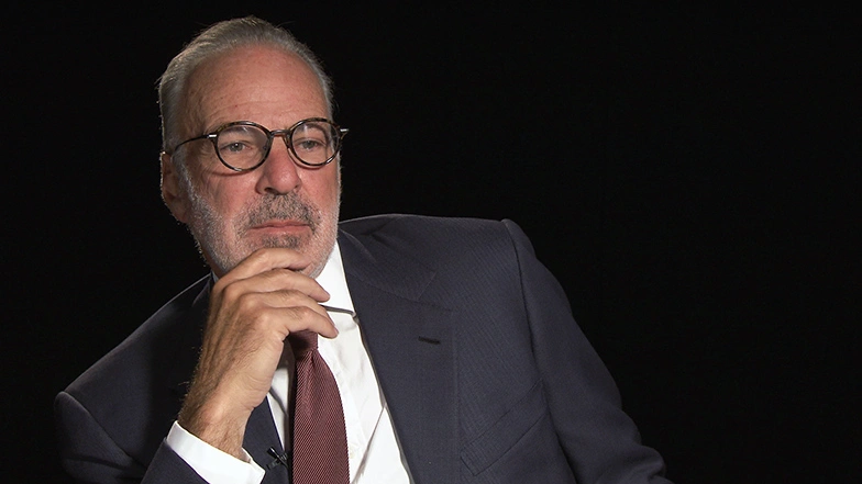 Robert Millard seated in front of a black background for an on camera interview.