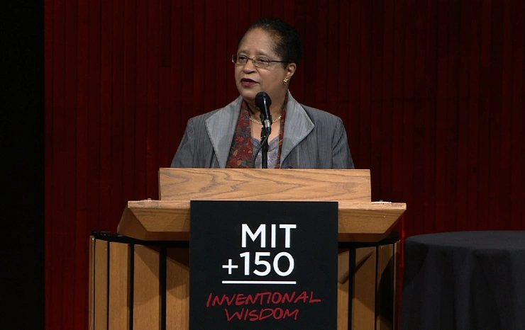 Shirley A. Jackson speaking at a podium on stage, in front of a dark background