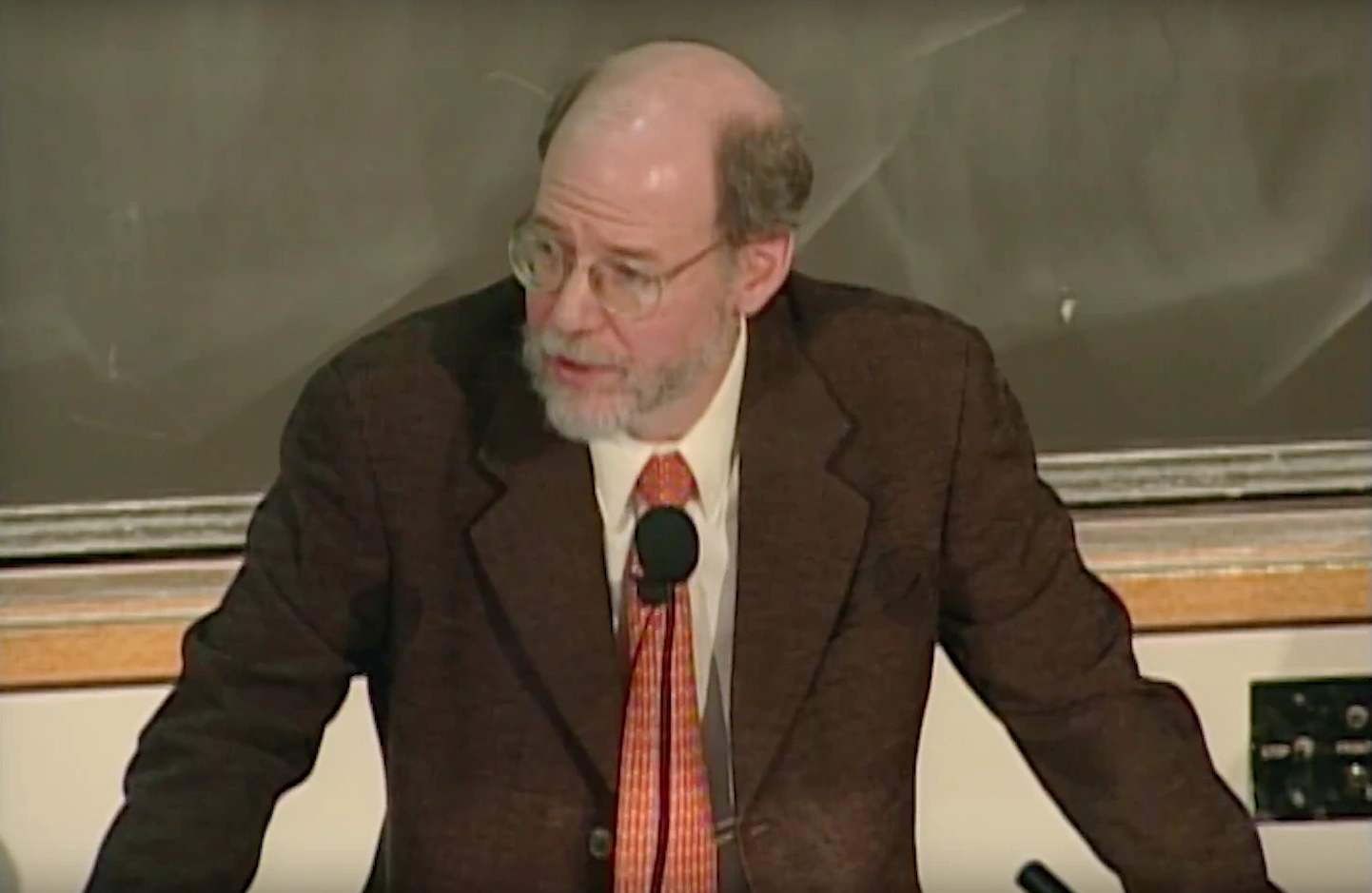 Robert Horvitz standing at podium in classroom, with a chalkboard in the background.