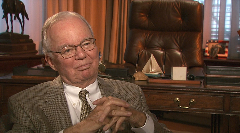 Howard Johnson is seated in elegant executive office, in place for an on camera interview, hands clasped.