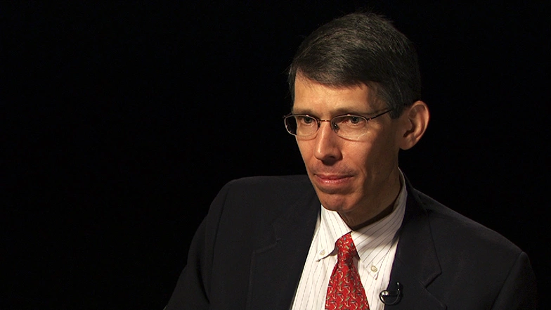 James Poterba seated in front of a black background for an on camera interview.