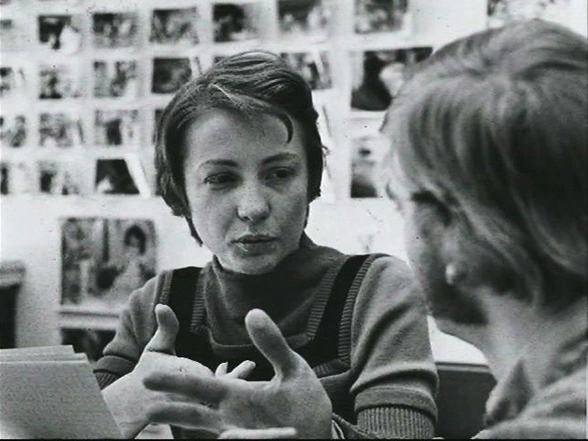 Margaret MacVicar seated outside speaking to a man facing toward her.
