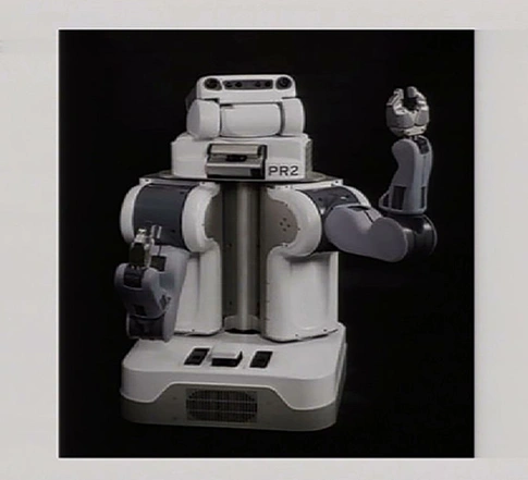 An early robot holds a metal arm up to wave, a graphic image