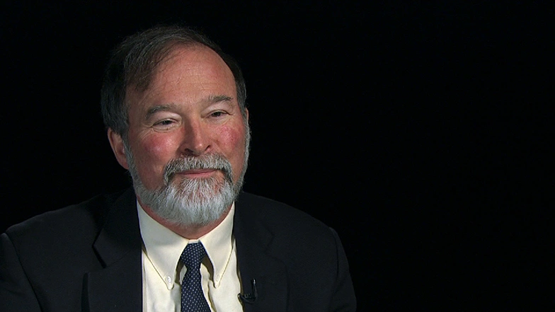 Robert Redwine seated in front of a black background for an on camera interview.