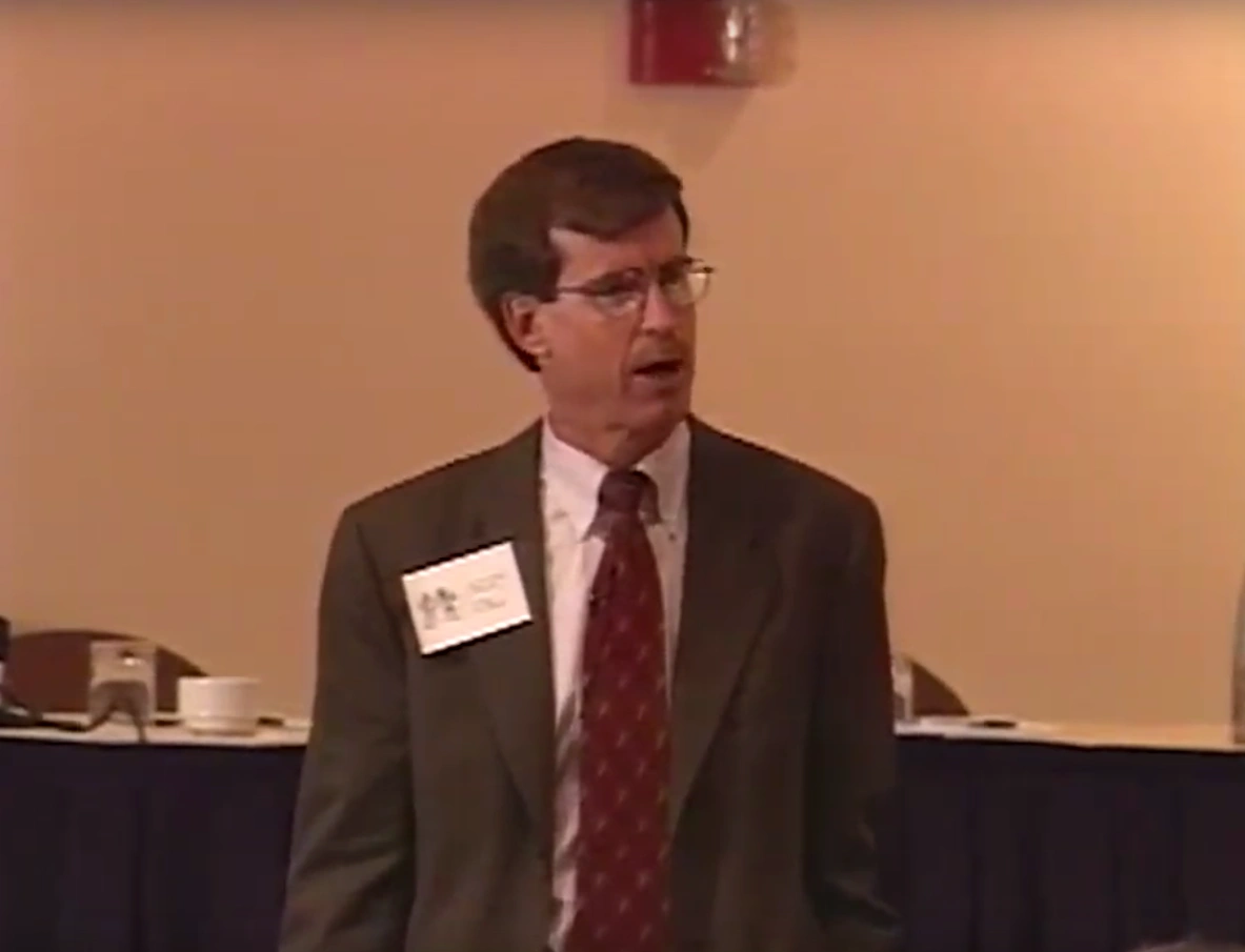 E. Daniel Hirleman Jr. standing and speaking in a classroom with white walls.