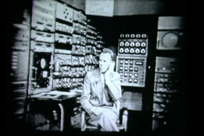 Over exposed black and white photo of Jay W. Forrester sitting at computer 