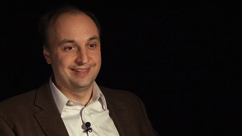 Vladmir Bulovic seated in front of a black background for an on camera interview, smiling.