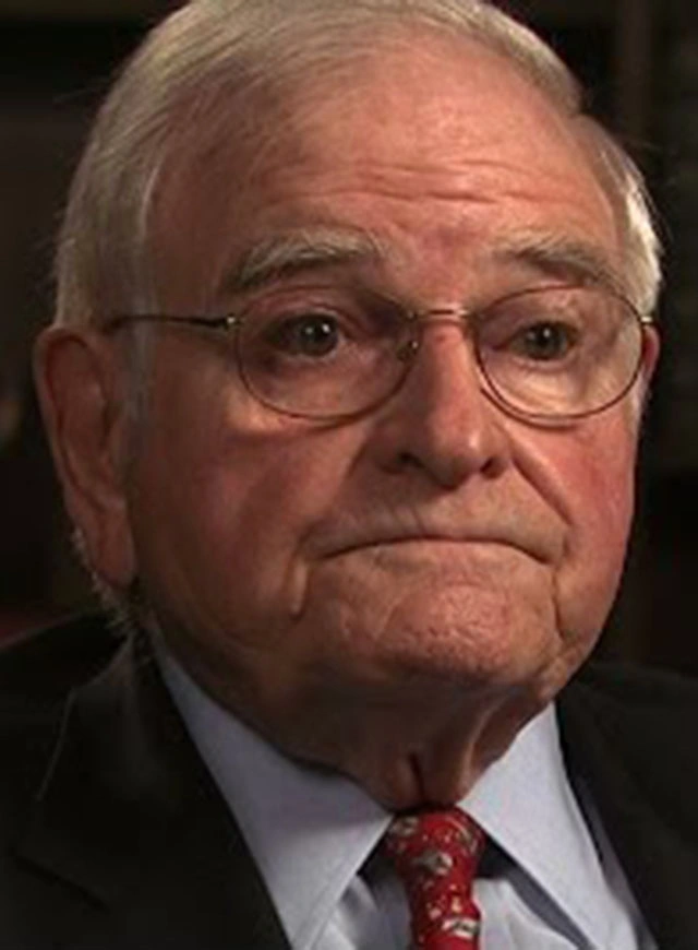 Paul E. Gray seated in front of a black background for an on camera interview.
