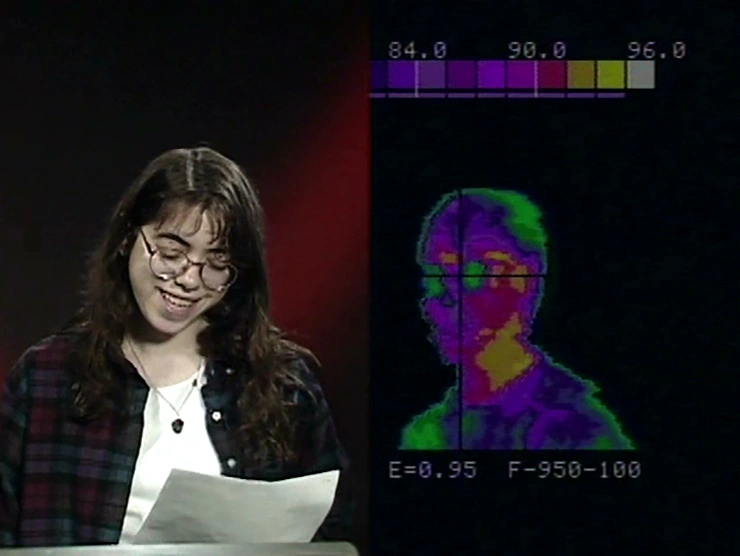 A woman smiles looking at a printed sheet of paper in hand, a holographic photo of student ahead of her