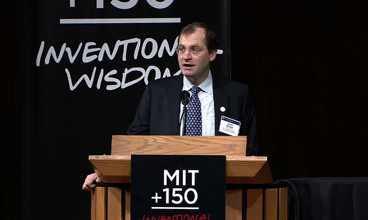 David Mindell speaking at a podium onstage for MIT150 Symposium