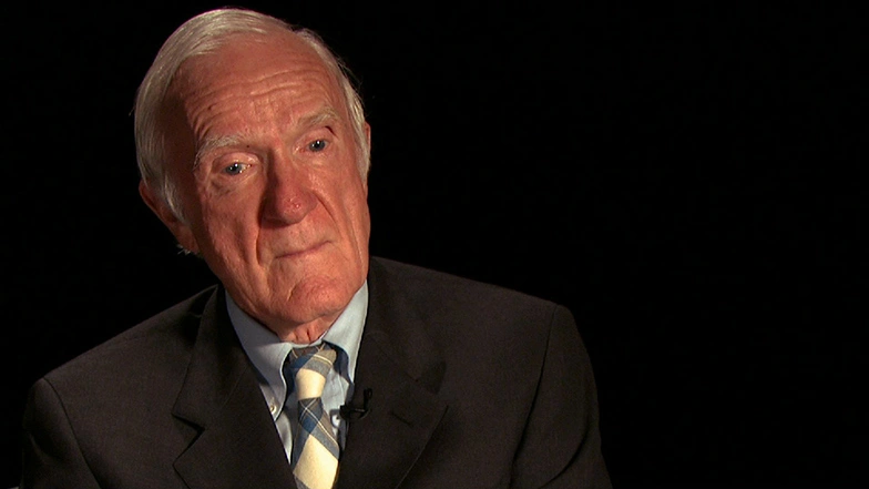 Paul Penfield seated in front of a black background for an on camera interview.
