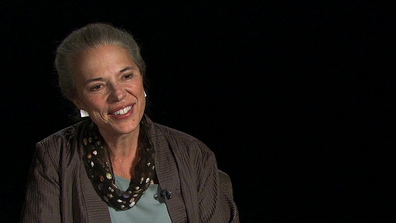 Kathryn Willmore seated in front of a black background for an on camera interview, smiling.