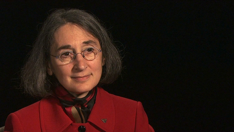 Karen W. Arenson seated in front of a black background for an on camera interview.
