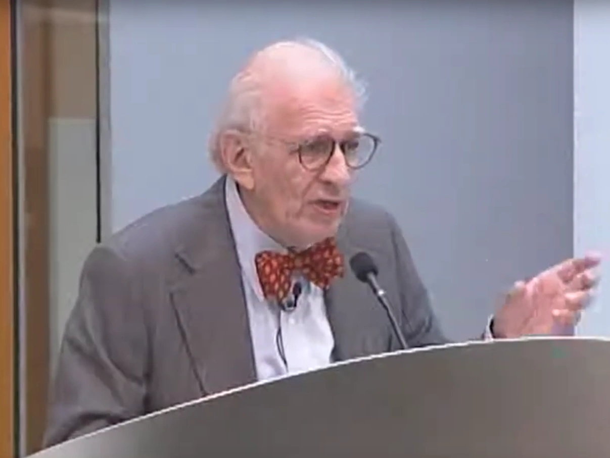 Eric Kandel speaks at a podium in front of a gray background
