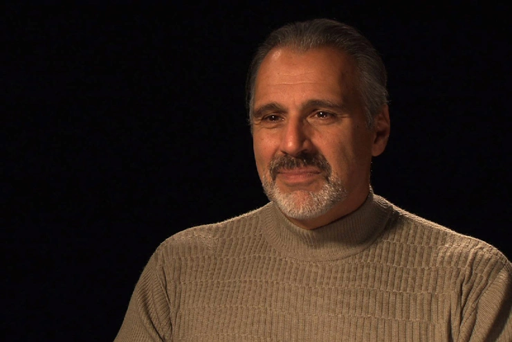 John DiFava seated in front of a black background for an on camera interview.