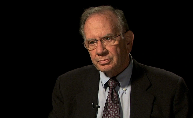 Daniel Roos seated in front of a black background for an on camera interview.