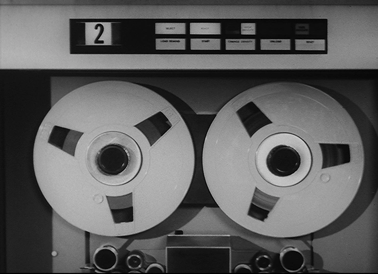 Two reels of tape winding around spools in a large machine