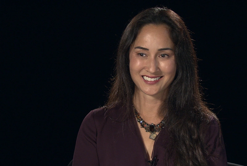 Cynthia Breazeal seated in front of a black background for an on camera interview.