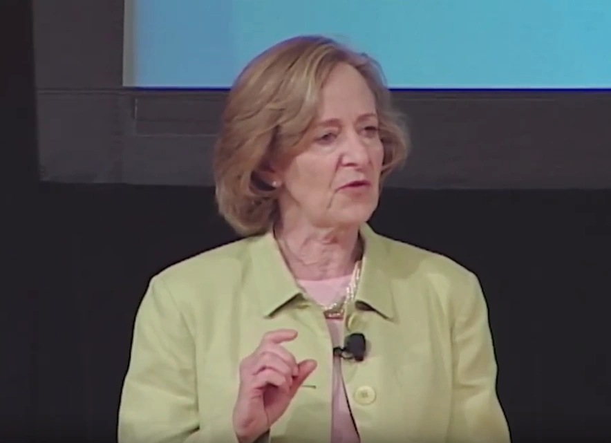 Susan Hockfield speaking at podium onstage in front of a blank projector screen