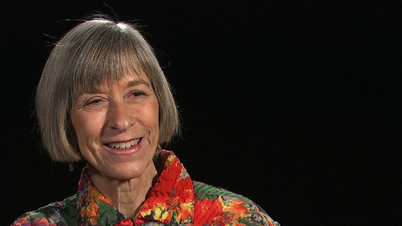 Rosalind Williams seated in front of a black background for an on camera interview, smiling