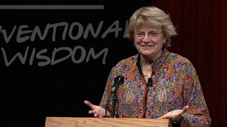 Nancy H. Hopkins speaking at a podium on stage, in front of a dark background