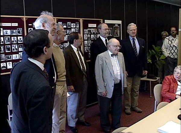 A group of Nobel Laureates from MIT gather in front of stage.