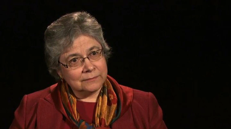 Ellen Harris seated in front of a black background for an on camera interview.