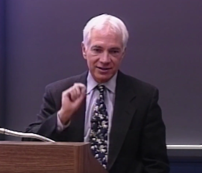 Claude R. Canizares lecturing at a podium in front of a chalkboard