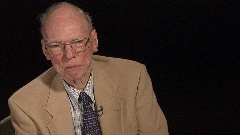 Walter E. Morrow, Jr. seated in front of a black background for an on camera interview.