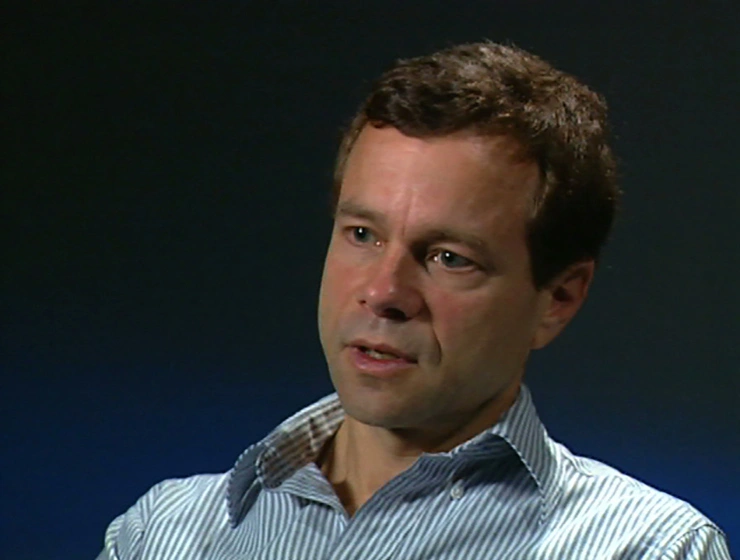 Alan Lightman seated in front of a black background for an on camera interview.