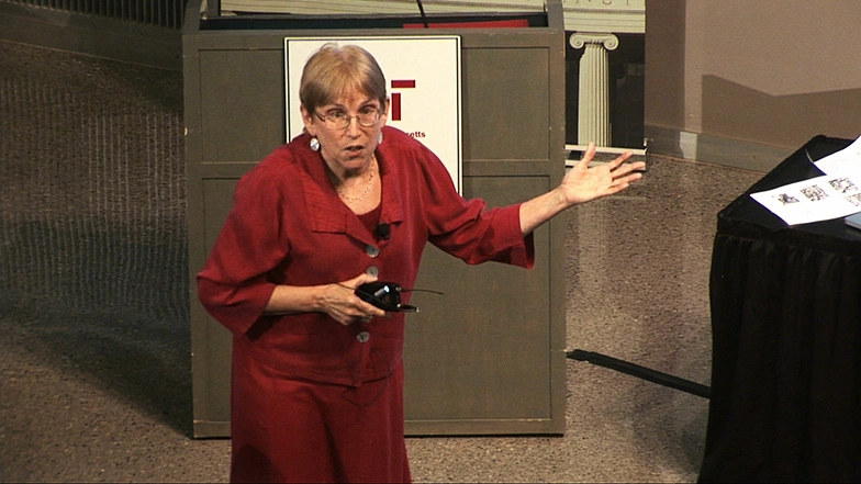 JoAnne Stubbe speaks onstage in front of podium.