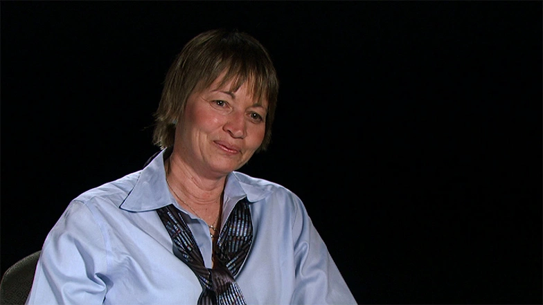 Maria T. Zuber seated in front of a black background for an on camera interview, smiling