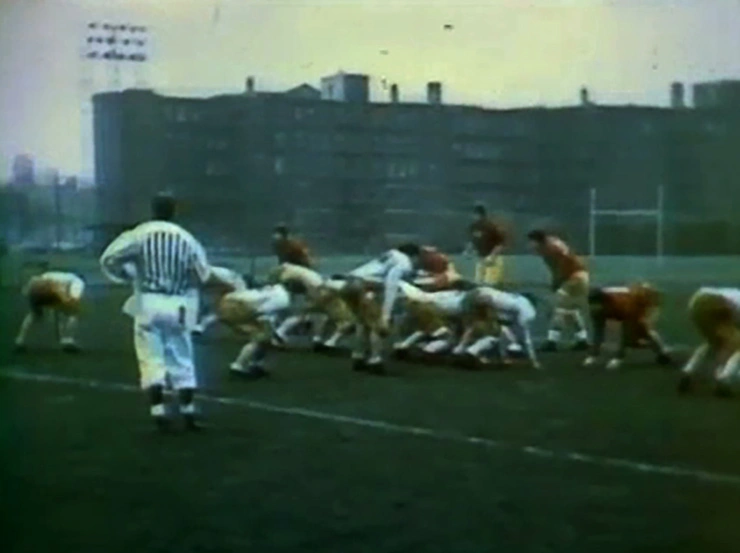 Refree looking away from camera in front of MIT football players in scrimmage line
