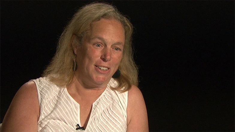 Martha L. Gray seated in front of a black background for an on camera interview.