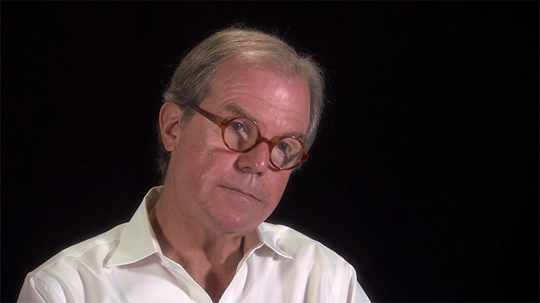 Nicholas Negroponte seated in front of a black background for an on camera interview.