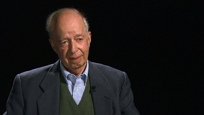Eugene B. Skolnikoff seated in front of a black background for an on camera interview.