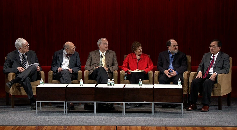 Panel of Turing Award winners seated on stage for discussion, red curtain in the background
