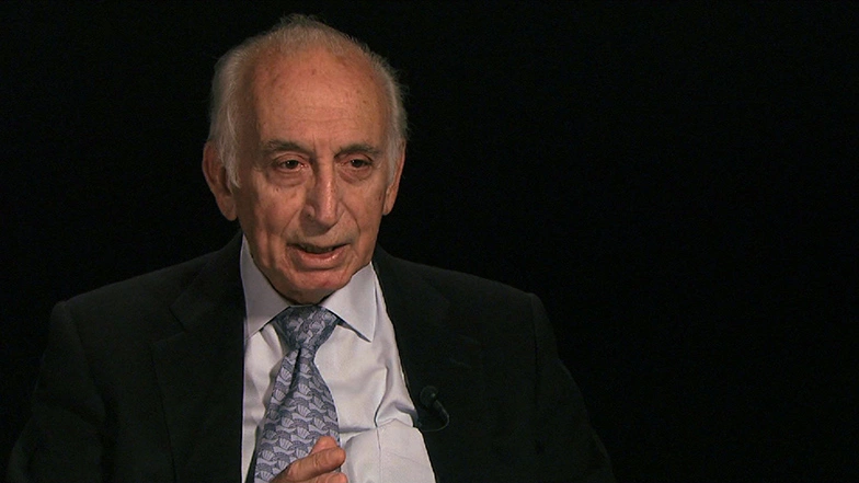 George N. Hatsopoulos seated in front of a black background for an on camera interview.